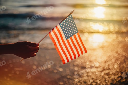 Preview: Candid authentic gen Z boy keep American Flag by hand on sea background as symbol of democracy
