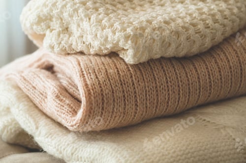Preview: Stack of Folded Knitted Sweaters in Soft Colors