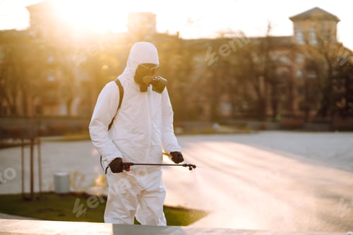 Preview: A man wearing special protective disinfection suit sprays sterilizer in the public place. Covid -19.
