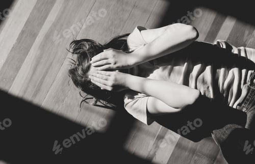 Vista previa: Black and white image of a teen girl laying on the floor with her hands over her face
