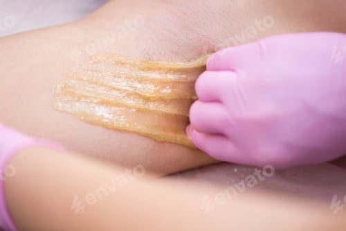 Preview: Professional woman at spa beauty salon doing epilation armpits using sugar.