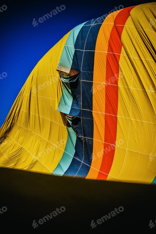 Preview: Detail of multicolored fabric of a hot air balloon deflating, vertical image.
