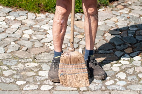 Preview: gardener in dirty work clothes and boots holds garden tools broom,seasonal spring work in the garden