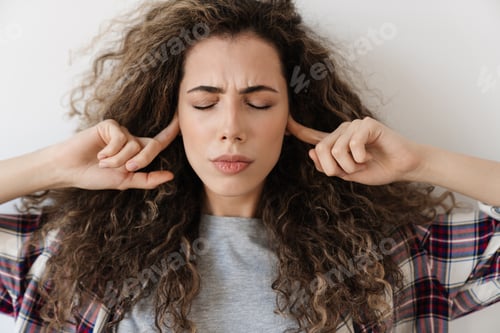 Preview: Photo of displeased woman plugging her ears while posing on camera