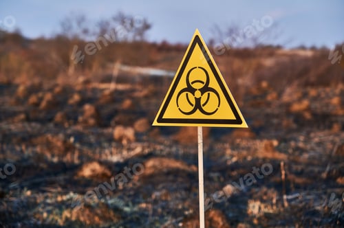 Preview: Yellow biohazard sign installed in scorched field with burnt anthills