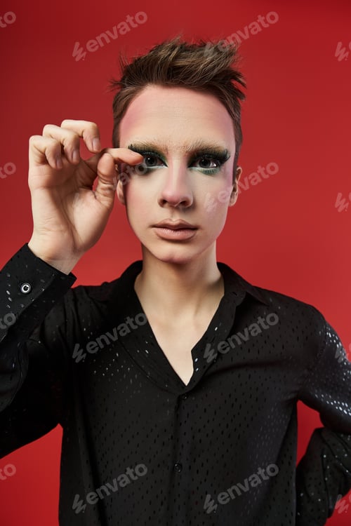 Preview: Young Drag Artist Posing Confidently Against a Bold Red Background in Stylish Ensemble