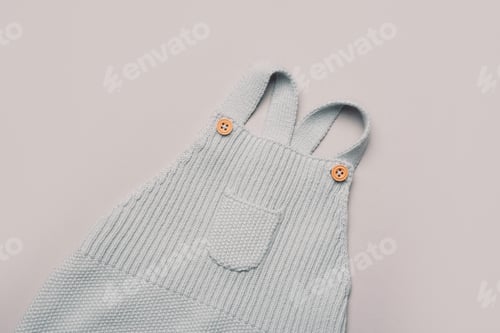 Preview: Pastel color knitted romper on grey background. Set of baby stuff and accessories