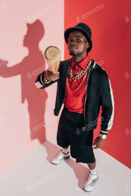 Preview: high angle view of young african american man with baseball bat pointing at camera