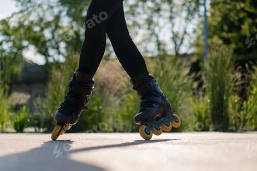 Preview: sporty girl practicing tricks on roller skates in park on city background enjoying roller