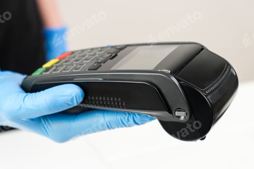 Preview: Close up woman in rubber gloves holding a pos terminal. Contactless payment during pandemic using