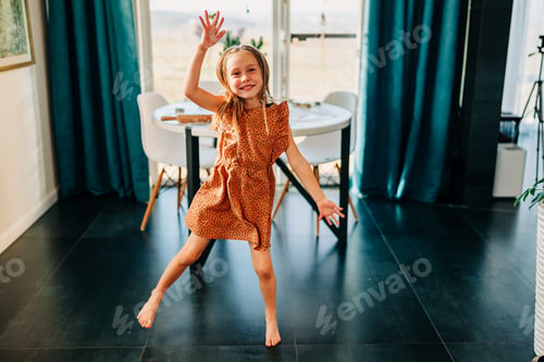 Preview: Little kid happy girl dancing on the kitchen at cozy home lifestyle authentic moment