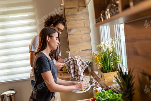 Preview: Woman doing the washing up while man is drying the dishes