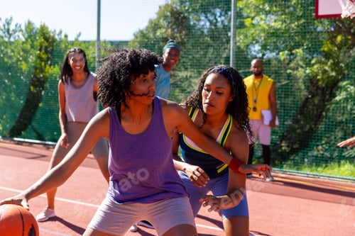 Preview: Happy diverse female friends with male coach playing basketball at basketball court