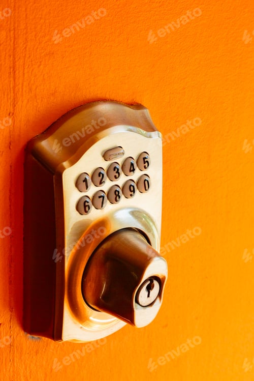 Preview: Electronic Door lock and key pad on an orange background, close up.