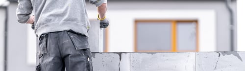 Preview: a mason builds a wall from concrete blocks. Banner with copy space