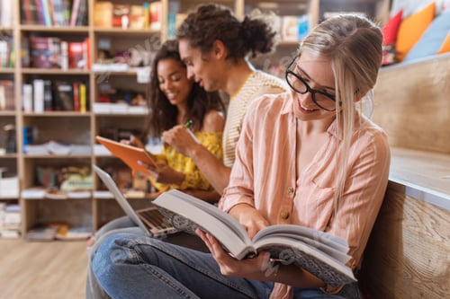 Preview: Three young students sitting on the floor in the library learning together.