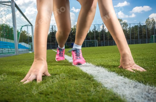 Preview: slim sporty woman getting ready to run on grass track