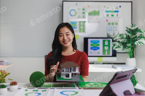 Preview: Woman presenting green building concept with model house