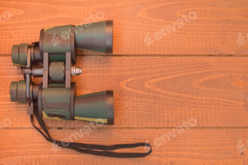 Preview: Binoculars protective khaki on wooden background, top view