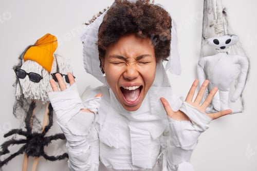 Preview: Photo of emotional curly haired woman screams loudly keeps mouth widely opened hands raised dressed