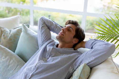 Preview: Young man relaxing on sofa at home