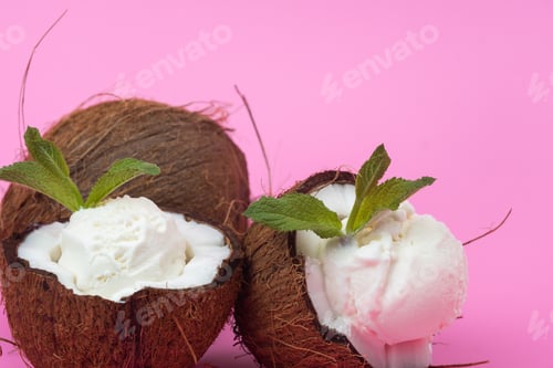 Preview: Vanilla ice cream balls in fresh coconut halves decorated with mint leaves on a pink background