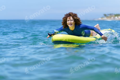 Preview: Cheerful woman pulling SUP board in seawater