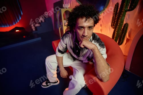 Preview: Cool Guy Posing in Armchair in Contemporary Art Space
