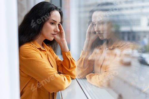 Preview: Woman experiencing stress, thinking near window reflection
