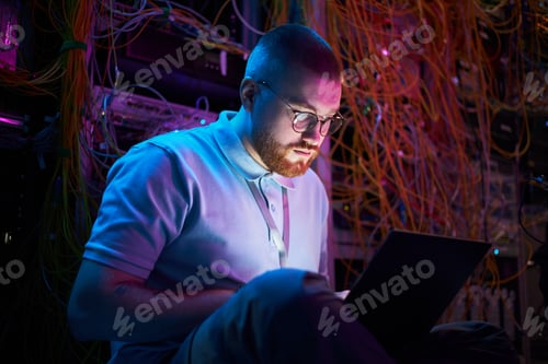 Preview: Portrait of Bearded Man Working on Laptop in Server Room