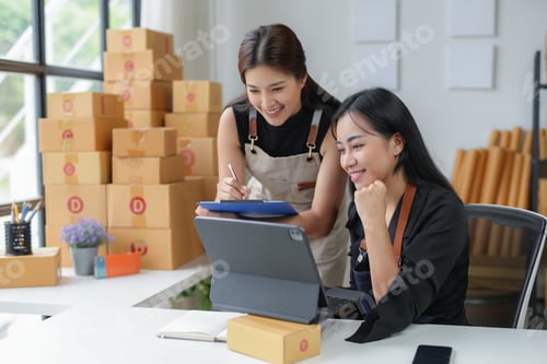 Preview: Two female entrepreneurs are smiling while working together in their startup office