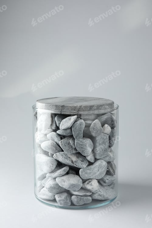 Preview: Presentation for product. Glass container with stones on light grey background. Space for text