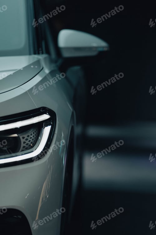 Preview: Vertical shot of the front - headlight and side mirror of white luxury car