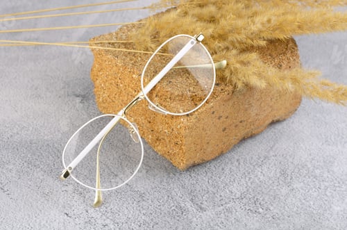 Preview: Glasses for vision in a white frame on a podium made of natural stone