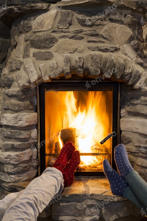 Preview: Cropped shot of two young women with feet up in front of fireplace