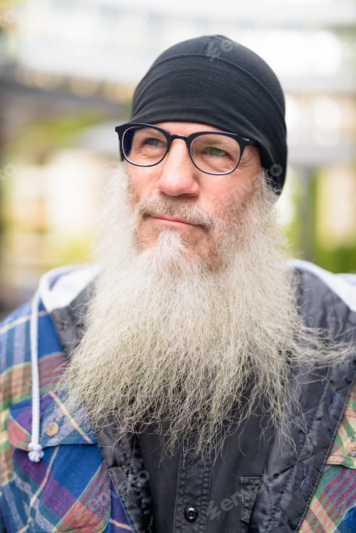 Preview: Face of mature bearded hipster man with eyeglasses thinking outdoors