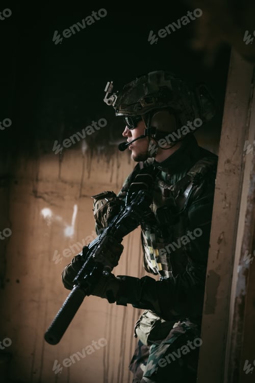 Preview: Military man with assault rifle standing inside building, he is ready for combat