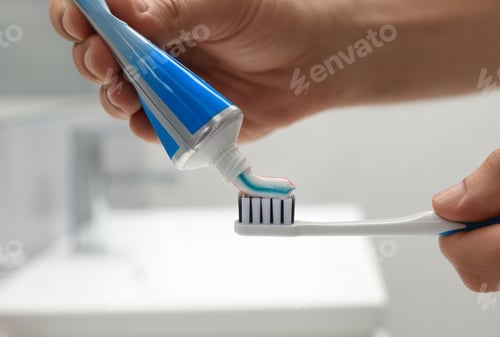 Preview: Man applying toothpaste on brush in bathroom, closeup