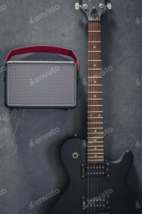 Preview: Electric guitar and speaker on a textured black background, top view.
