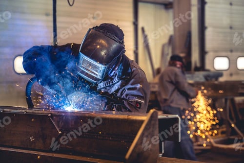 Preview: Skilled welder is seen at work in a large industrial factory, using a welding machine with sparks
