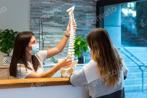Preview: Female doctor showing a spine model to a patient during a consultation at the physiotherapy center