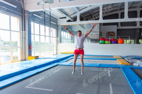 Preview: Fitness, fun, leisure and sport activity concept - Handsome happy man jumping on a trampoline