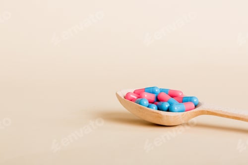 Preview: Vitamin capsules in a spoon on a colored background. Pills served as a healthy meal.