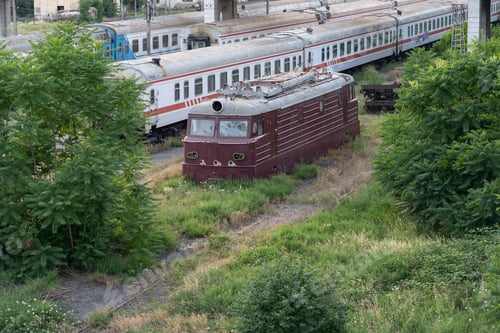 Preview: Abandoned soviet locomotive and passenger wagons on railroad tracks overgrown with grass