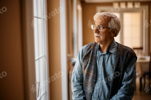 Preview: Pensive elderly man looking through the window at nursing home.