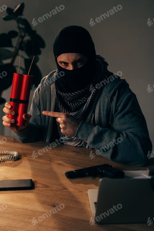 Preview: Angry terrorist in mask pointing with finger at dynamite in room