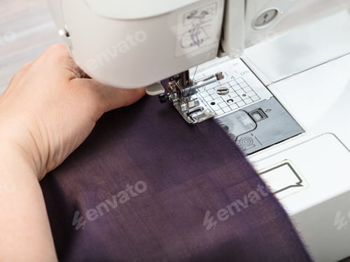 Preview: needlewoman sews strips of fabrics for patchwork