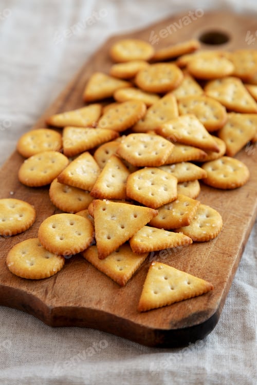 Preview: Homemade Salty Crackers on a Rustic Wooden Board, side view. Close-up.