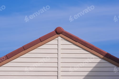 Preview: white artificial wooden gable roof with brown roof tile of vintage house against blue sky background