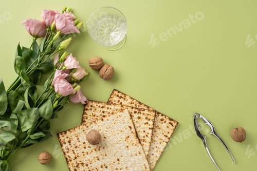 Preview: Flat lay composition of matzah, walnuts, a nutcracker, flowers, and a glass